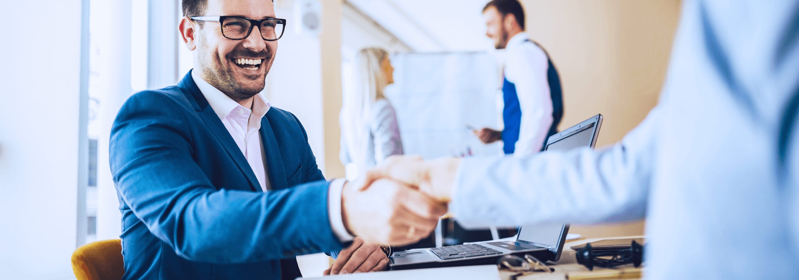 Immagine di uomo sorridente che stringe la mano a un partner commerciale - Satech